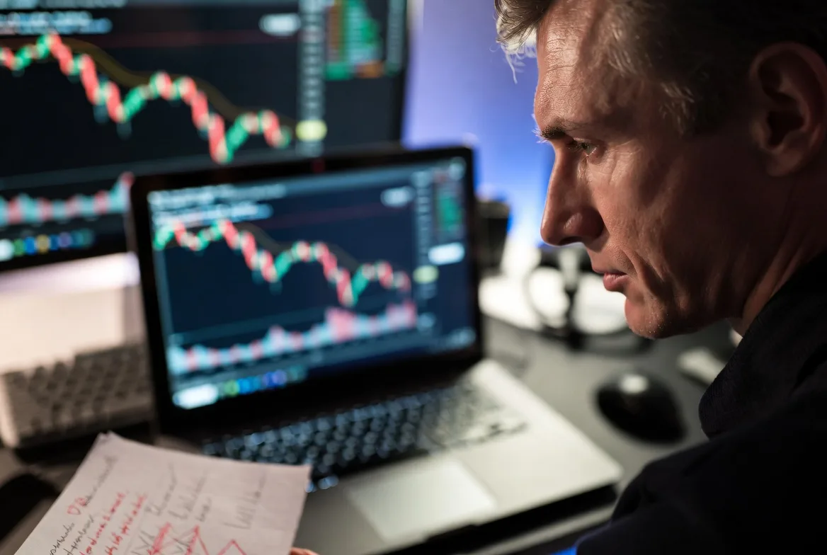 trader reacting to losses and market volatility on screen